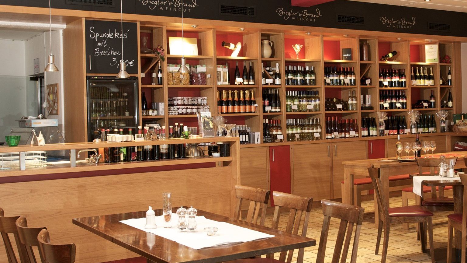 Weinrestaurant & Vinothek Kaisergarten - im Vordergrund ein eingedeckter Tisch und im Hintergrund ein Weinregal mit Weinen des Weinguts Biegler & Brand