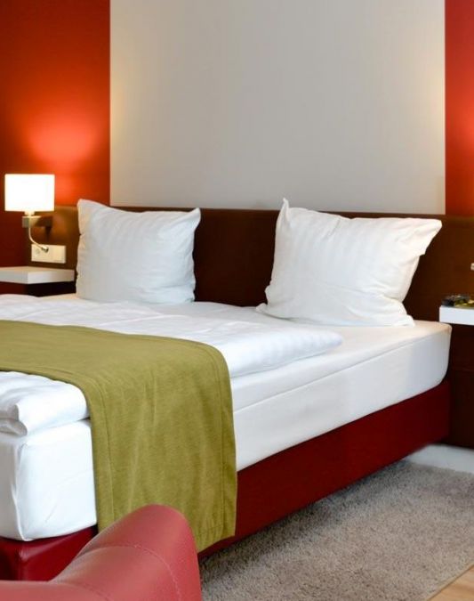 Zimmer der Kategorie Spaetlese im Weinhotel Kaisergarten Alzey Blick auf das grosszuegige Doppelbett die Farben des Weins dominieren