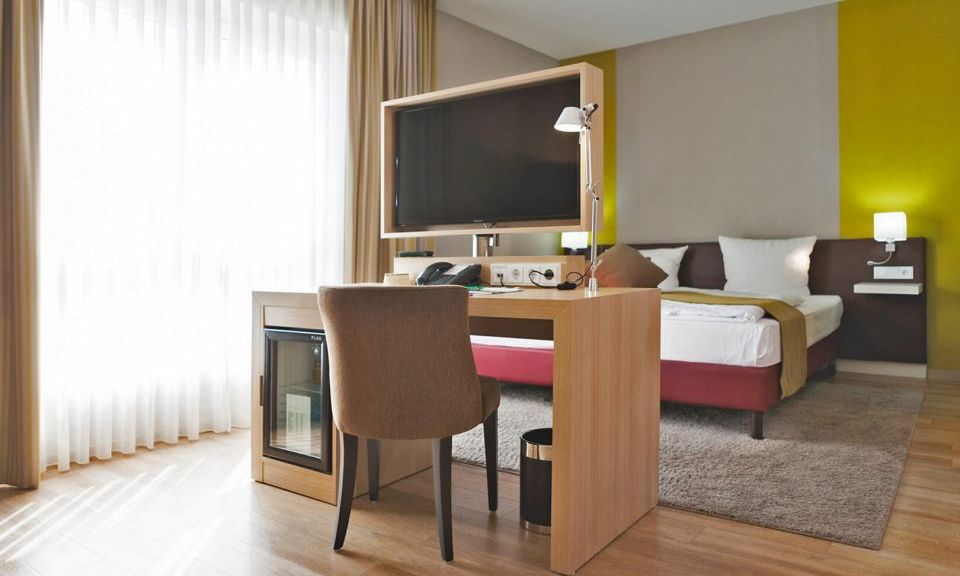 Blick in das Hotelzimmer der Kategorie Auslese im Weinhotel Kaisergarten in Alzey im Hintergrund das grosse Doppelbett und in der Mitte Schreibtisch mit drehbarem TV und Schreibtischstuhl  
