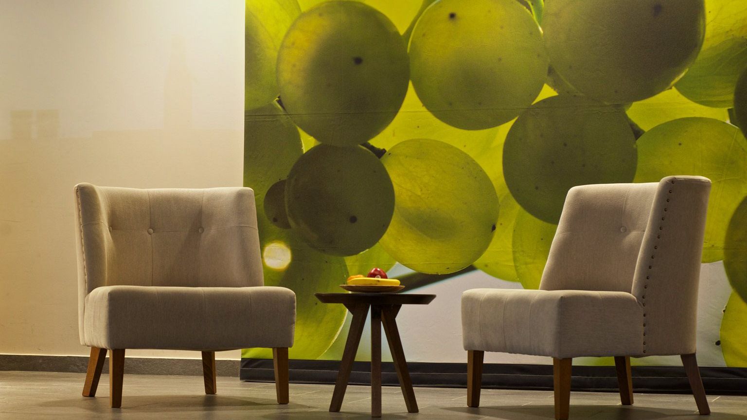 Two chairs and a small round table as designer furniture in the lobby of the Weinhotel Kaisergarten with a large photo of illuminated Riesling grapes on the wall