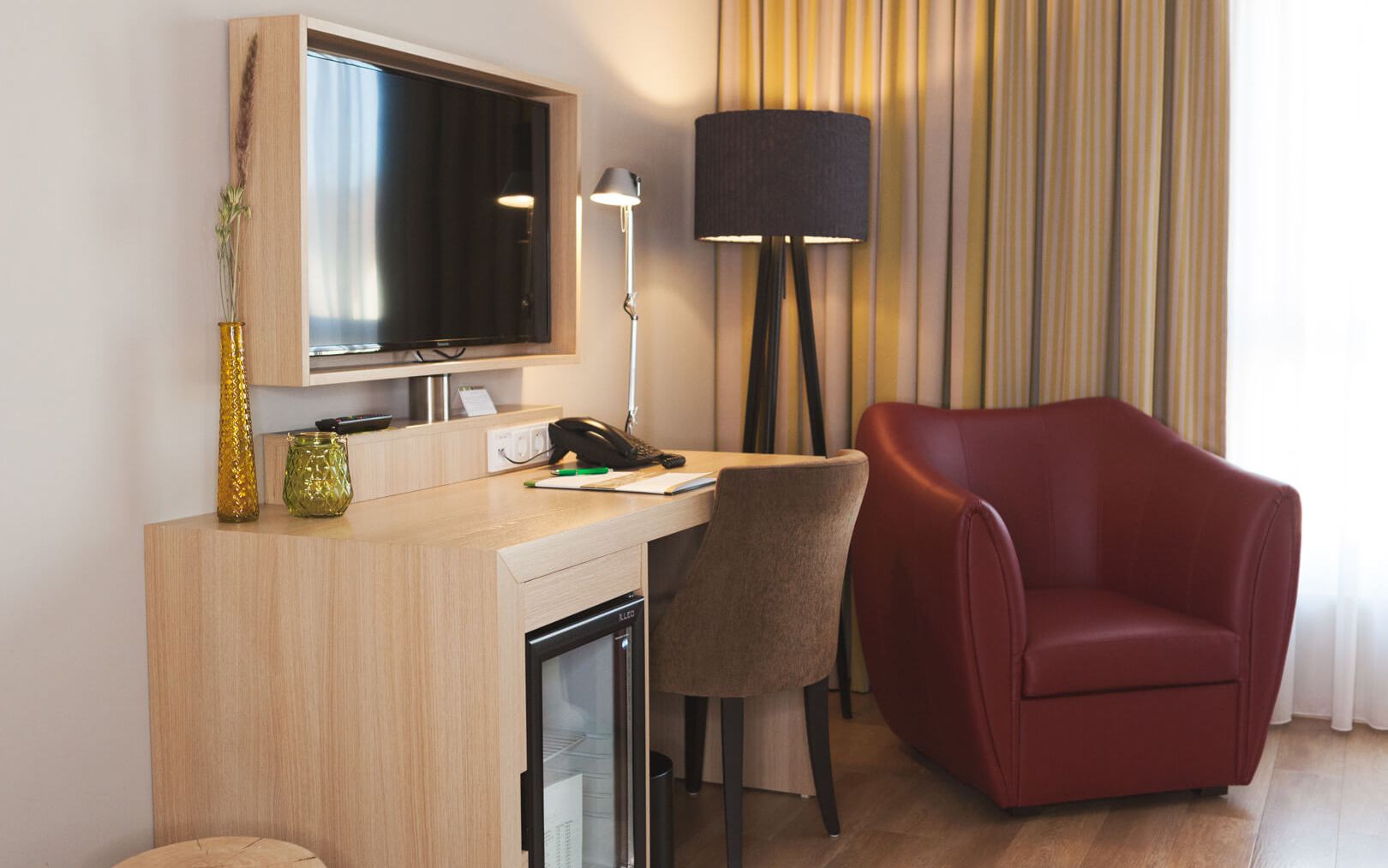 Hotel room in the Spätlese category at the Weinhotel Kaisergarten in Alzey in Rheinhessen with a view of the desk, armchair, TV and floor lamp