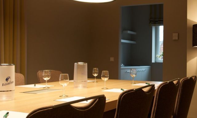 Tagungsraum Klassik Bestuhlung Blockform mit 8 Stuehlen, grosser TV an der Wand Designerleuchten ueber dem Tisch