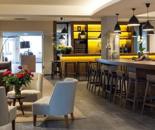 Lobby im Weinhotel Kaisergarten mit Designermobiliar 3 Stuehle ein grosses Sofa im Hintergrund links die Tuere zur Vinothek und rechts der Tresen der Weinbar