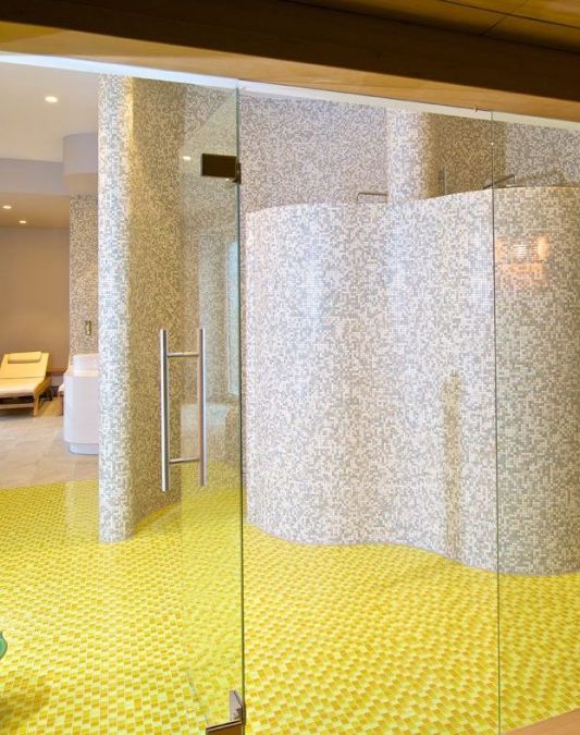 View from the sauna towards the wet area tiled in sunny yellow and beige in the sauna area of the Weinhotel Kaisergarten in Alzey