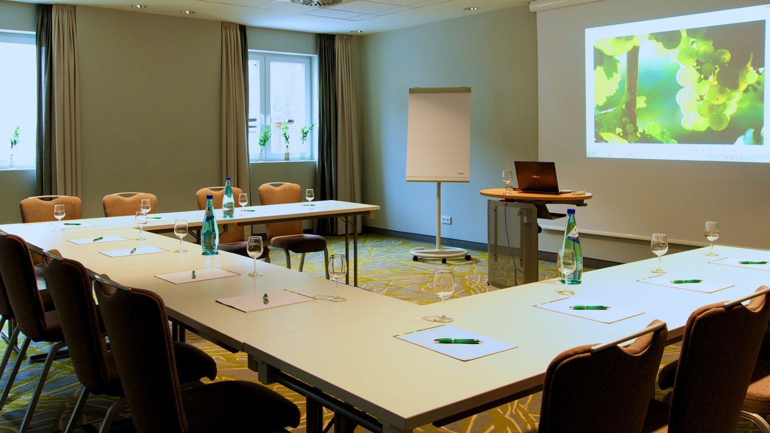 Meeting room on the ground floor Carpeted flooring Daylight U-shaped seating Water bottles, cooler Glasses
