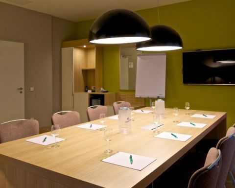 Tagungsraum Klassik Bestuhlung Blockform mit 8 Stuehlen, grosser TV an der Wand Designerleuchten ueber dem Tisch