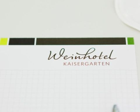 Writing pad chequered with logo of the Weinhotel Kaisergarten and pen tip on the conference table