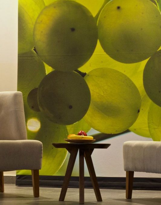 Two chairs and a small round table as designer furniture in the lobby of the Weinhotel Kaisergarten with a large photo of illuminated Riesling grapes on the wall