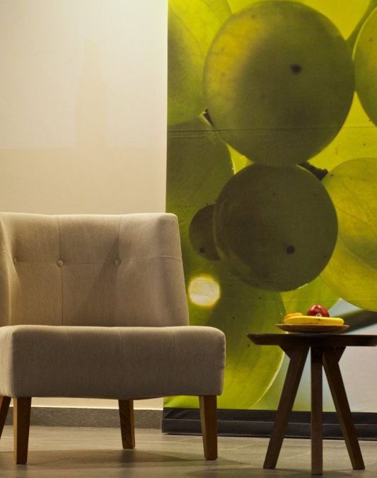 Two chairs and a small round table as designer furniture in the lobby of the Weinhotel Kaisergarten with a large photo of illuminated Riesling grapes on the wall