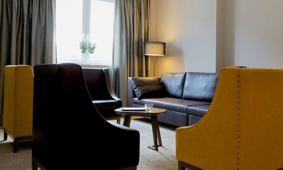 View of the master bedroom with three heavy leather armchairs, a leather couch, designer lamps and a solid wooden table