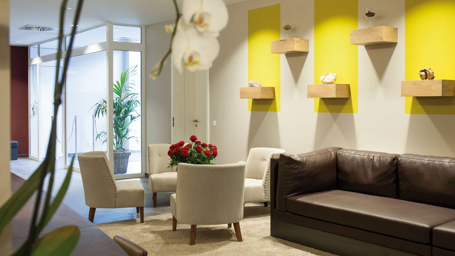 Lobby im Weinhotel Kaisergarten mit Designermobiliar 3 Stuehle ein grosses Sofa im Hintergrund links die Tuere des Hoteleingangs