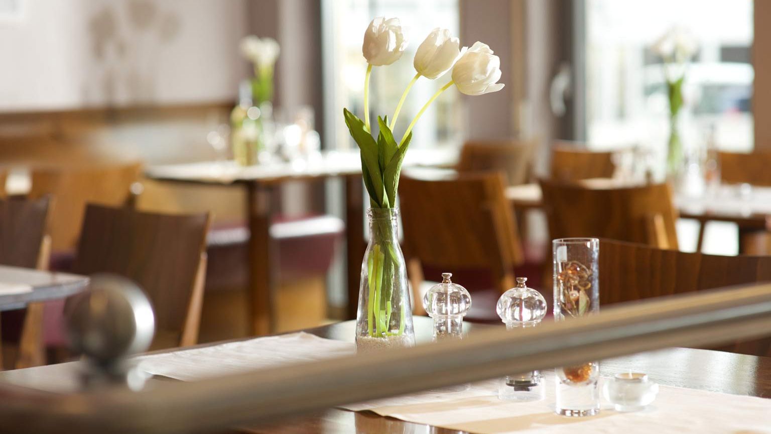Blick auf Tische mit Blumenschmuck im Weinrestaurant & Vinothek Kaisergarten in Alzey