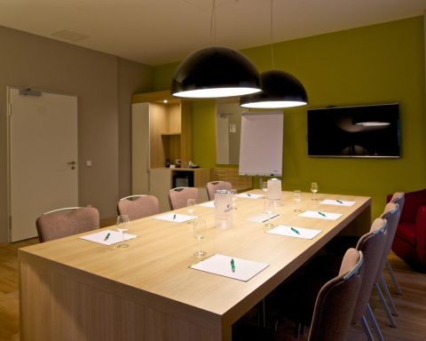 Conference room Classic Block seating with 8 chairs, large TV on the wall Designer lights above the table