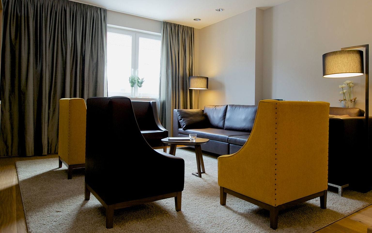 View of the master bedroom with three heavy leather armchairs, a leather couch, designer lamps and a solid wooden table