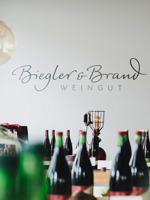 Blick in die Vinothek im Weinhotel Kaisergarten im Vordergrund einige Flaschen Wein hinten an der Wand der gemalte Schriftzug des Weinguts Biegler & Brand  