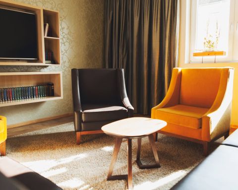 A view of the Herrenzimmer as a conference room with three heavy leather armchairs, a leather couch, designer lamps and an oversized screen for presentations or TV.