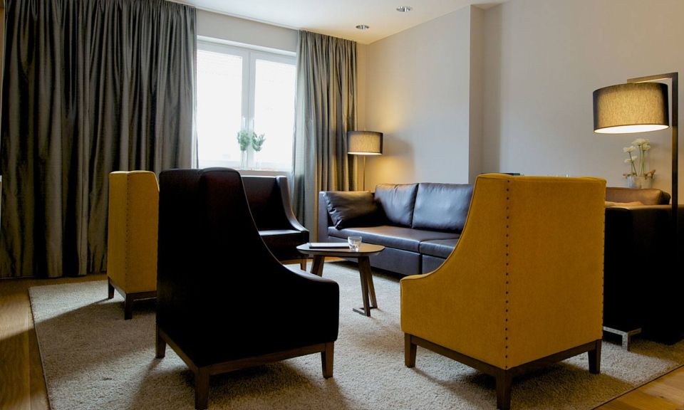 View of the master bedroom with three heavy leather armchairs, a leather couch, designer lamps and a solid wooden table