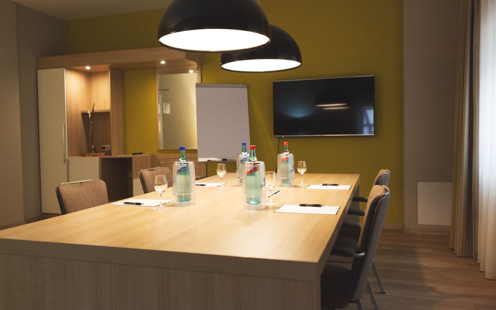 Conference room Classic Block seating with 8 chairs, large TV on the wall Designer lights above the table
