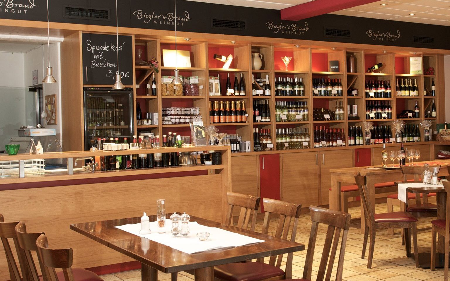 Weinrestaurant & Vinothek Kaisergarten - in the foreground a set table and in the background a wine rack with wines from the Biegler & Brand winery