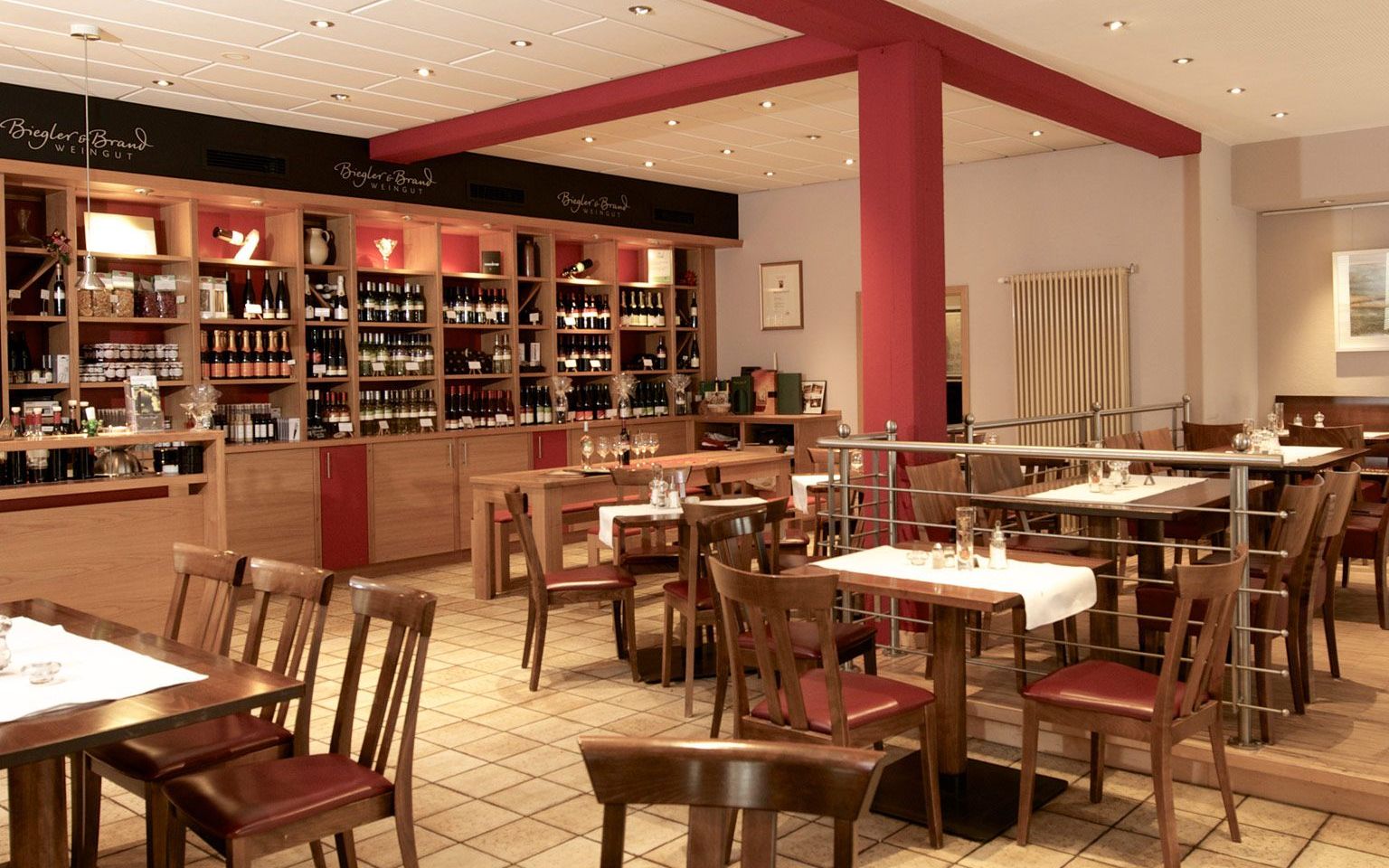Kaisergarten wine restaurant & vinotheque - tables laid out and a wine rack with wines from the Biegler & Brand winery in the background