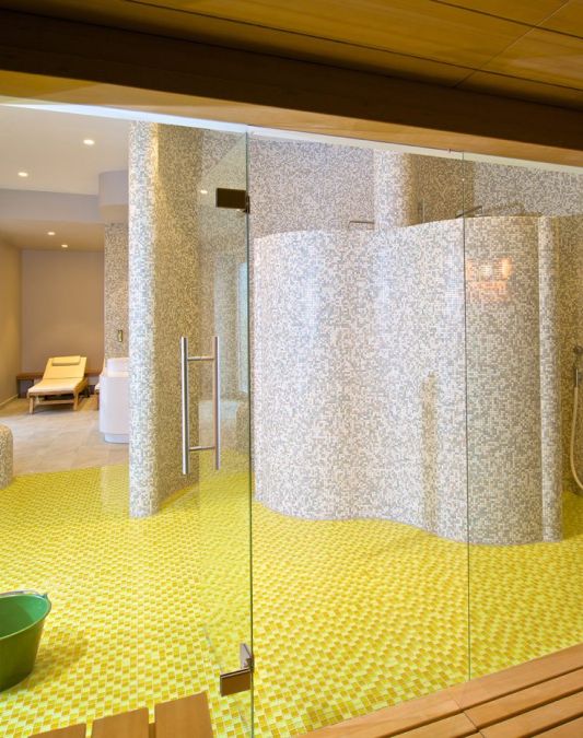 View from the sauna towards the wet area tiled in sunny yellow and beige in the sauna area of the Weinhotel Kaisergarten in Alzey