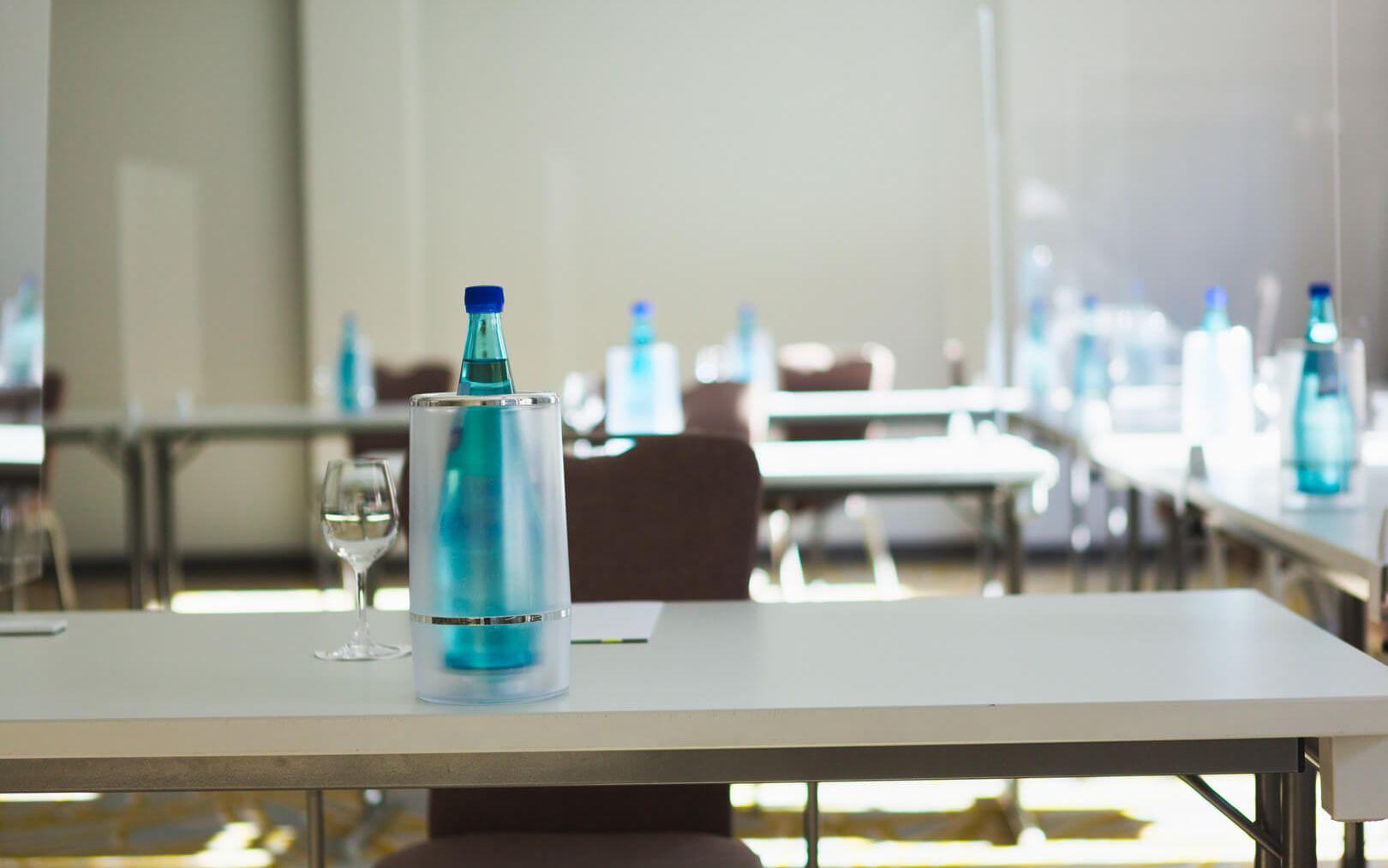 Conference room on the ground floor Daylight U-shaped seating The conference tables have a water bottle and a cooler Glasses on the table