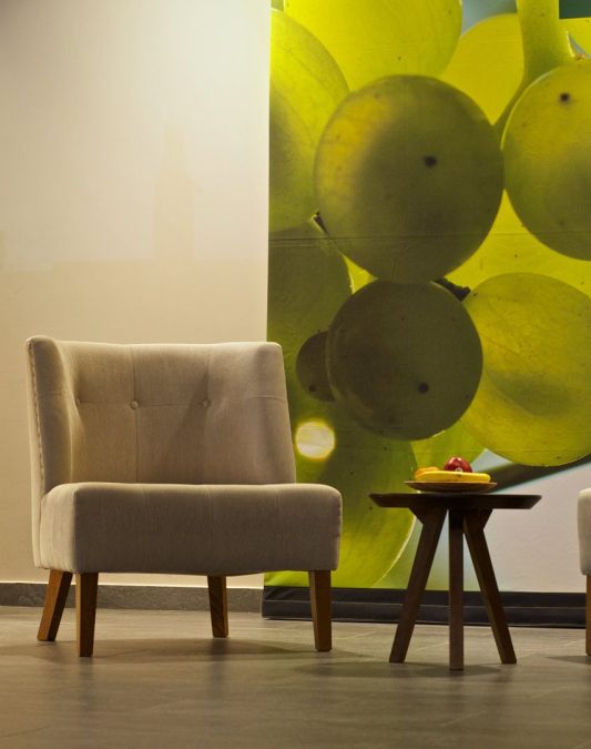 Two chairs and a small round table as designer furniture in the lobby of the Weinhotel Kaisergarten with a large photo of illuminated Riesling grapes on the wall